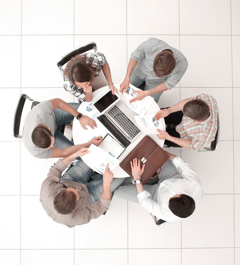 A photo of six people around a table having a business meeting