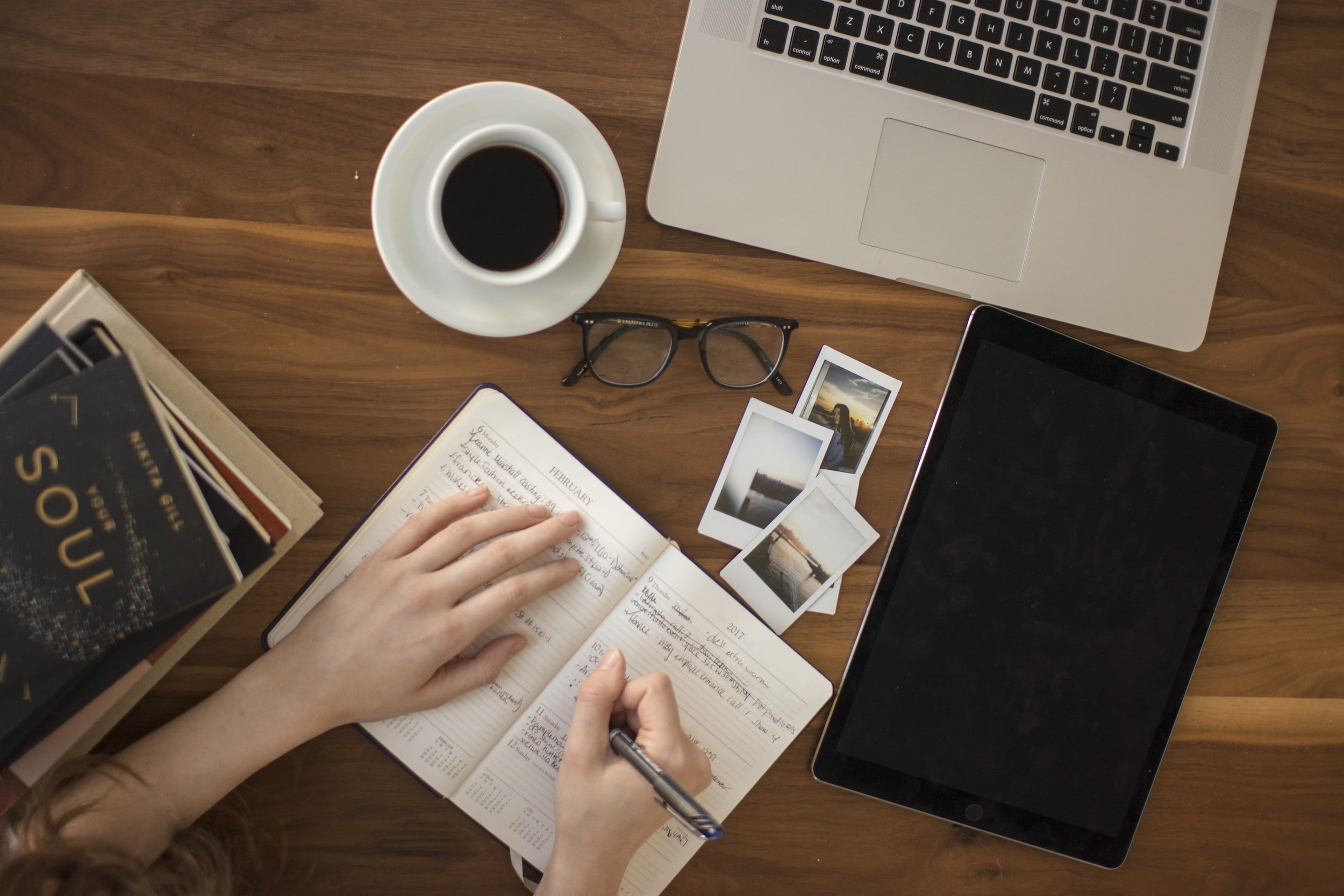 A photo showing a student taking notes and gadgets on a table